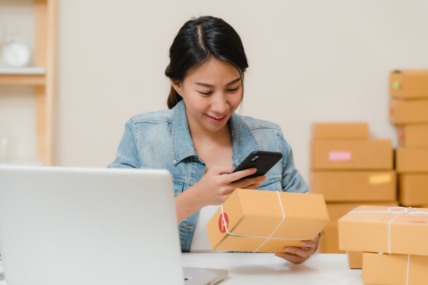 Seller checking orders on a phone beside packed parcels